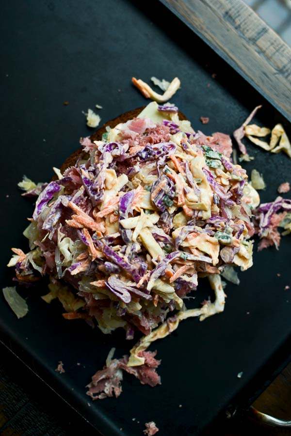 Creamy coleslaw with shredded cabbage, carrots, and purple cabbage on a black surface, perfect for summer BBQs and sandwiches. Fresh, crunchy, and flavorful.