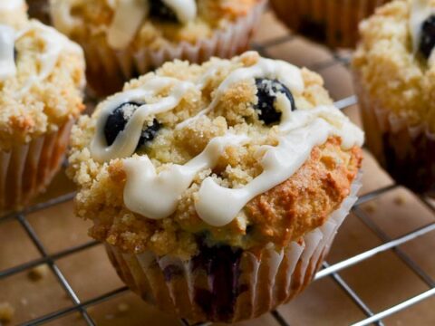Butterfly cupcakes with blueberry topping and white icing drizzle, baked muffins on cooling rack, sweet and indulgent dessert treats, perfect for parties and gatherings, bakery-style cupcakes, crumb topping details.