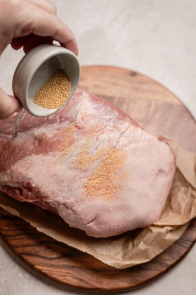 pork shoulder being seasoned