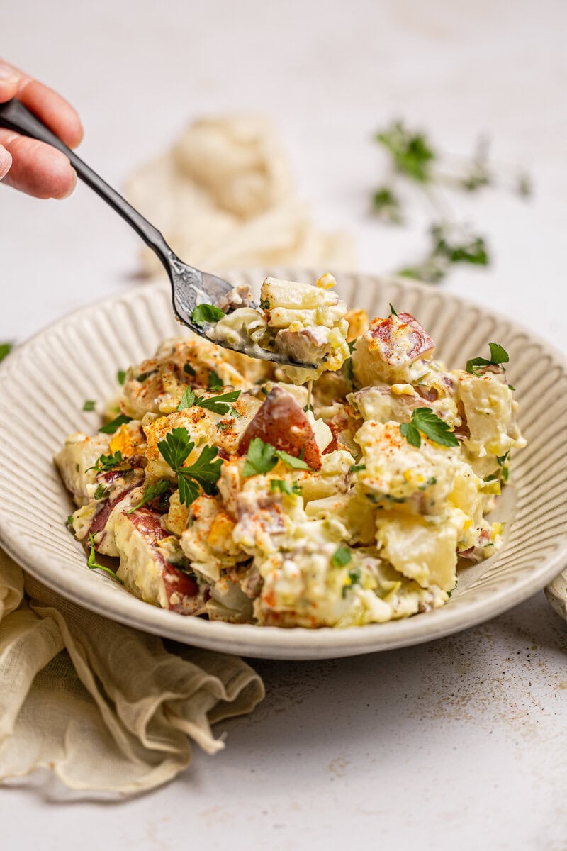 Creamy potato salad with fresh herbs and bacon bits, served in a rustic bowl, perfect for summer picnics and family gatherings. A classic side dish full of flavor.