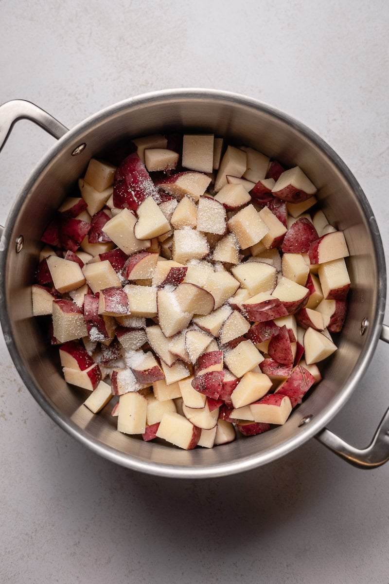Diced red and white apples with sugar in stainless steel pot for apple pie filling.