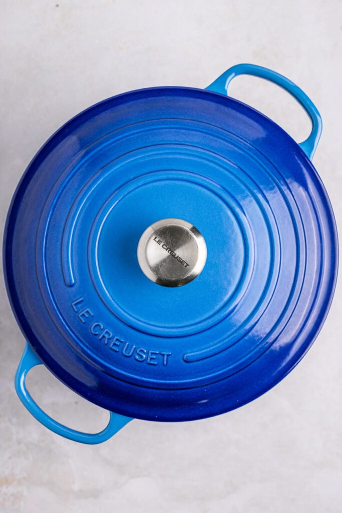 Shallow blue Le Creuset cast iron Dutch oven with lid, top view, ideal for baking and cooking, high-quality kitchen cookware.