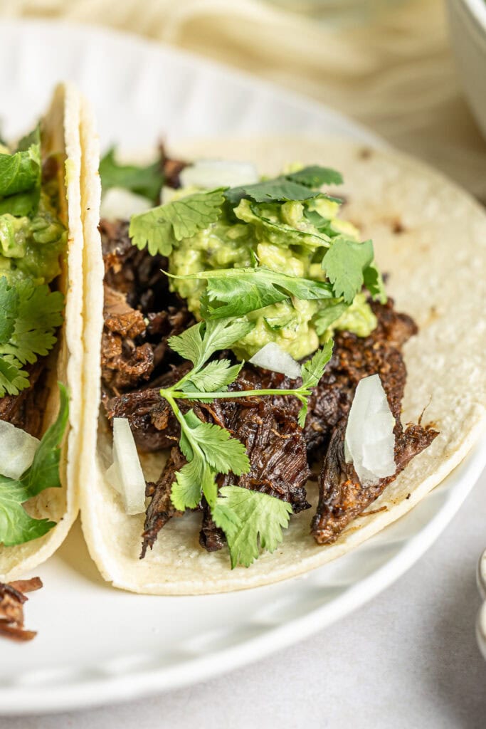 Juicy shredded beef tacos with fresh guacamole, cilantro, and onions served on soft corn tortillas. Perfect for Mexican-inspired meals or Taco Tuesday celebrations.
