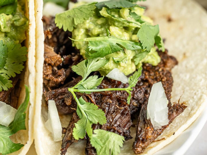 Juicy shredded beef tacos with fresh guacamole, cilantro, and onions served on soft corn tortillas. Perfect for Mexican-inspired meals or Taco Tuesday celebrations.