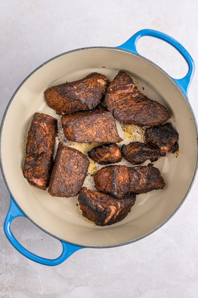 Juicy, well-seasoned beef short ribs with a rich, smoky crust cooked to perfection in a blue Dutch oven. Perfect for comfort food lovers and meat enthusiasts.