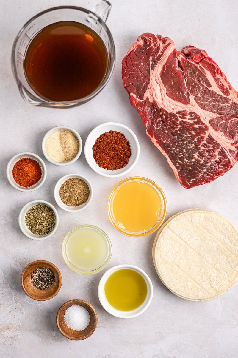 Tender beef, seasoned spices, broth, and cheese on a white surface, ideal for crafting delicious stuffed beef tortillas or similar savory recipes.