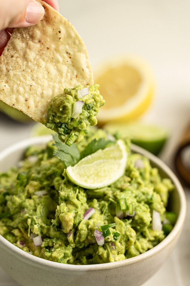 Creamy avocado guacamole with chopped onions and lime wedges served with a crispy tortilla chip. Perfect for snacking, parties, or as a delicious appetizer. Fresh, flavorful, and easy to make.