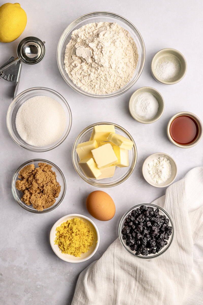 Flour, butter, sugar, eggs, blueberries, lemon zest, vanilla extract, and baking ingredients for blueberry lemon cake preparation. Fresh baking supplies for delicious sweet treats.