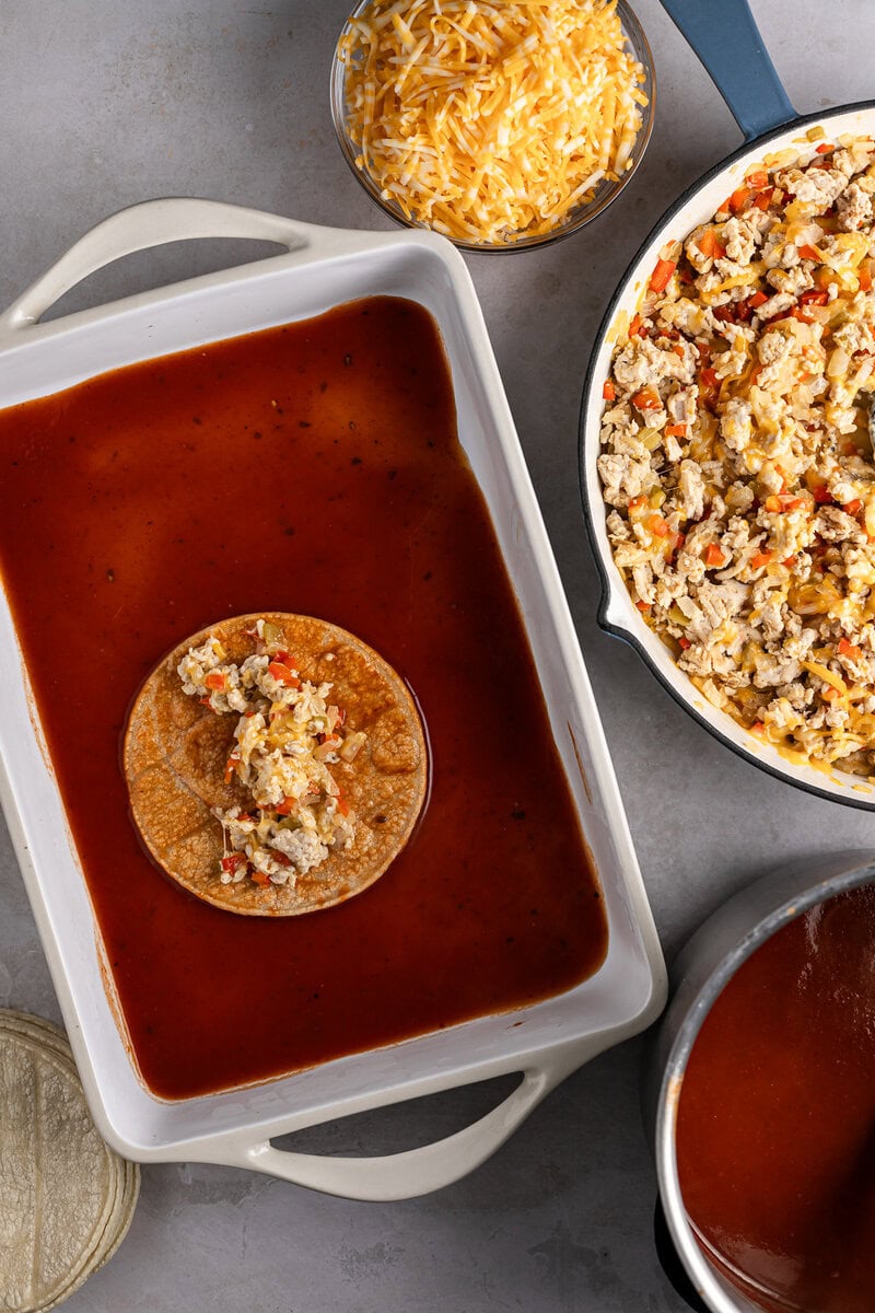 Soft taco with seasoned ground beef and toppings in a baking dish, shredded cheese in a bowl, and skillet with cooked beef and vegetables, perfect for homemade taco night at Stuck On Sweet.