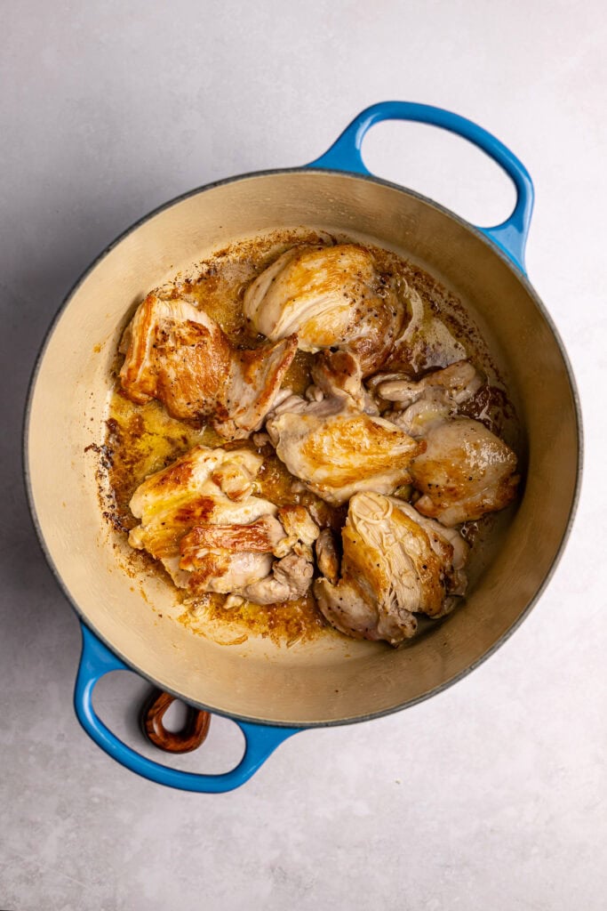 Juicy, golden-brown chicken thighs cooking in a Dutch oven, perfect for sweet and savory recipes.