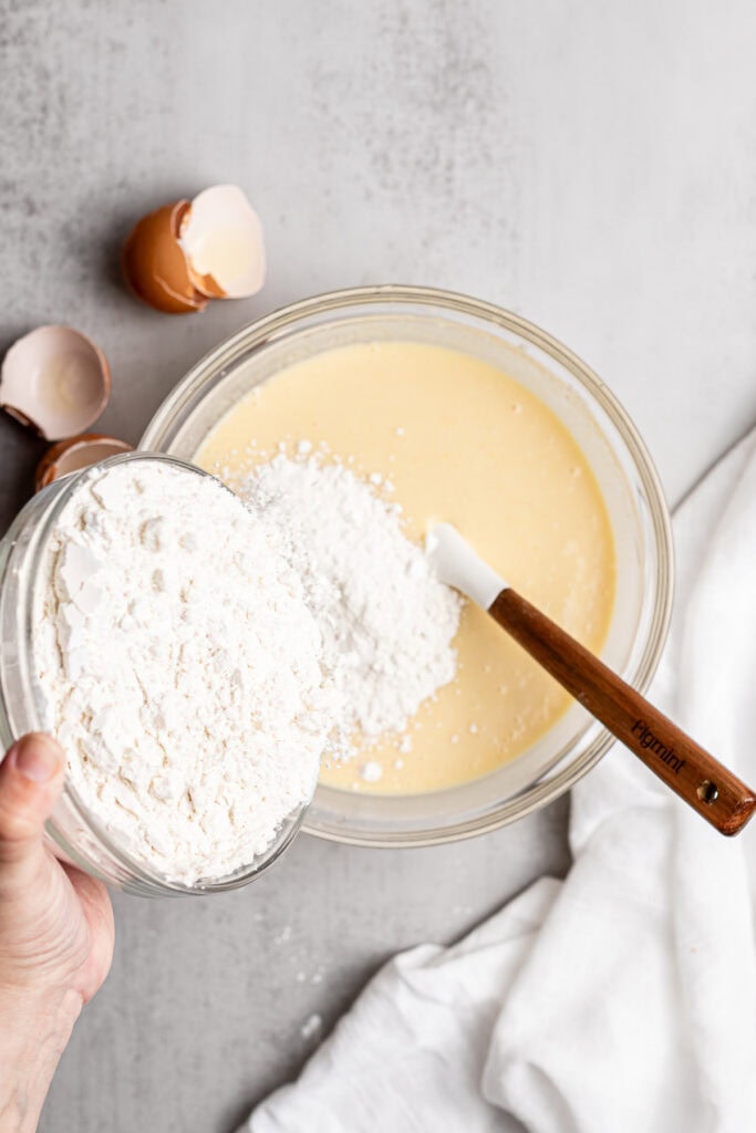 Cracked eggs and flour being added to cake batter for homemade baking recipes.