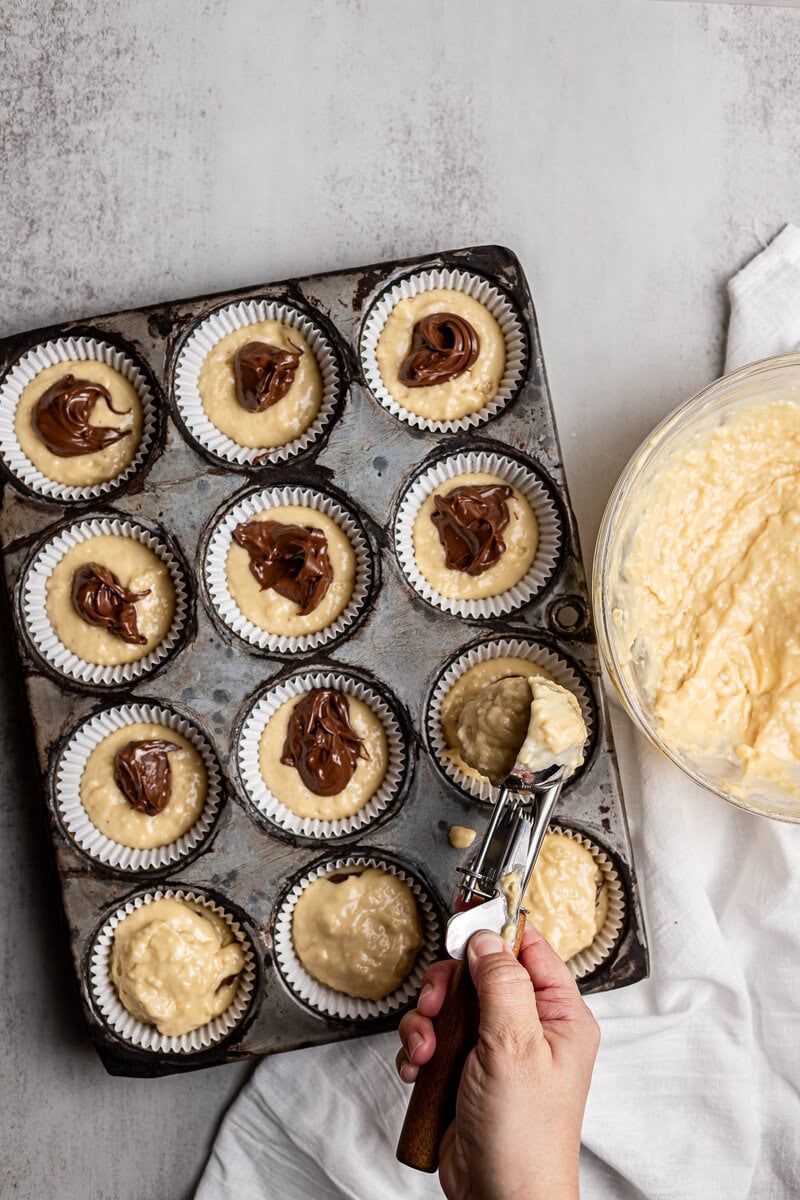 Vegan cupcake batter with chocolate and vanilla swirls in muffin tin for baking.