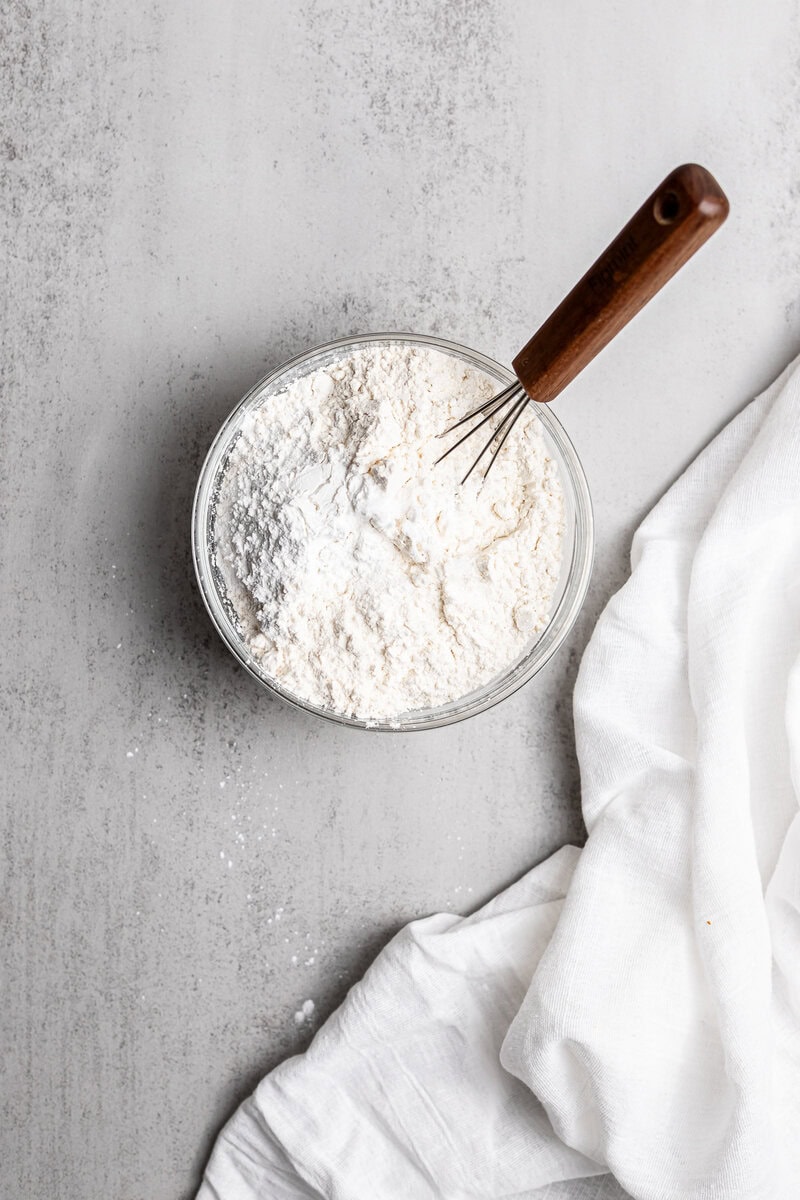 Flour in glass bowl with mixing whisk, baking ingredients for sweet recipes.