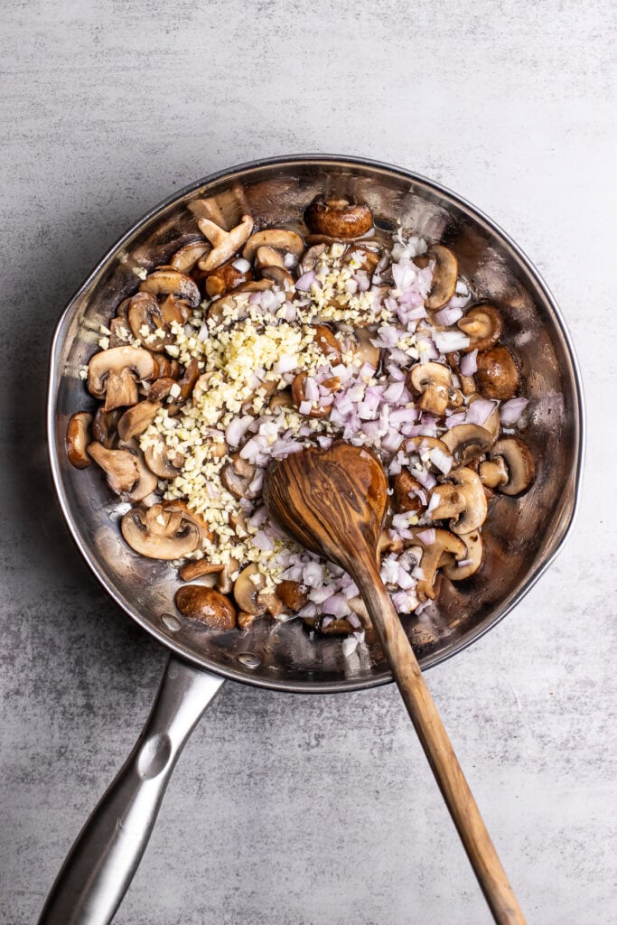 Sautéed mushrooms, garlic, and onions in a stainless steel pan, ready for recipe preparation.
