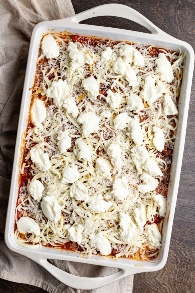 Creamy ricotta and mozzarella cheese layered on baked pasta dish, topped with grated cheese.
