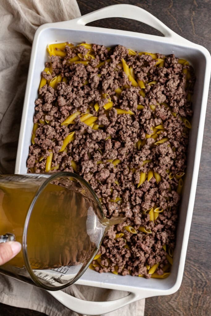 Creamy beef and pasta casserole baking dish with ground beef, pasta, and savory sauce on a wooden surface.