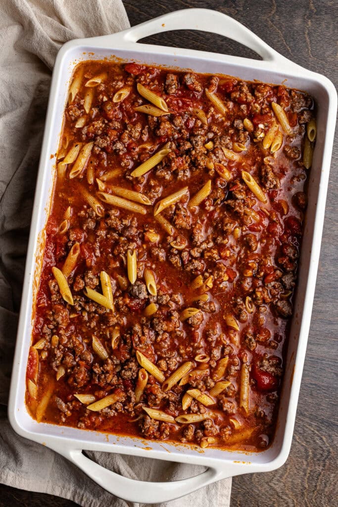 Rich homemade baked ziti with ground beef, pasta, and marinara sauce in a white casserole dish. Perfect comfort food recipe for family dinners and meal prep.