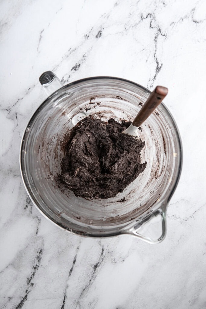 Rich chocolate cookie dough in a glass mixing bowl for baking.