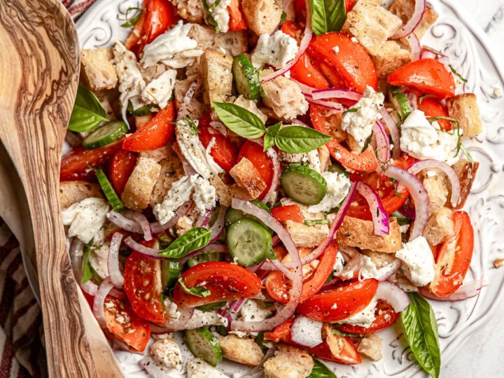 Fresh Tomato Caprese Salad with Basil, Red Onion, and Croutons on a White Plate.