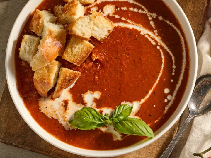 Creamy tomato basil soup served with toasted garlic bread croutons and fresh basil garnish,Perfect comfort food, vegan-friendly, ideal for lunch or dinner in cozy restaurants.