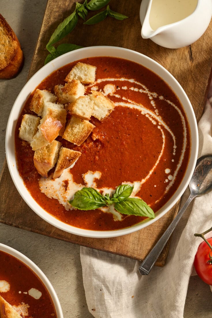 Creamy tomato basil soup served with toasted garlic bread croutons and fresh basil garnish,Perfect comfort food, vegan-friendly, ideal for lunch or dinner in cozy restaurants.