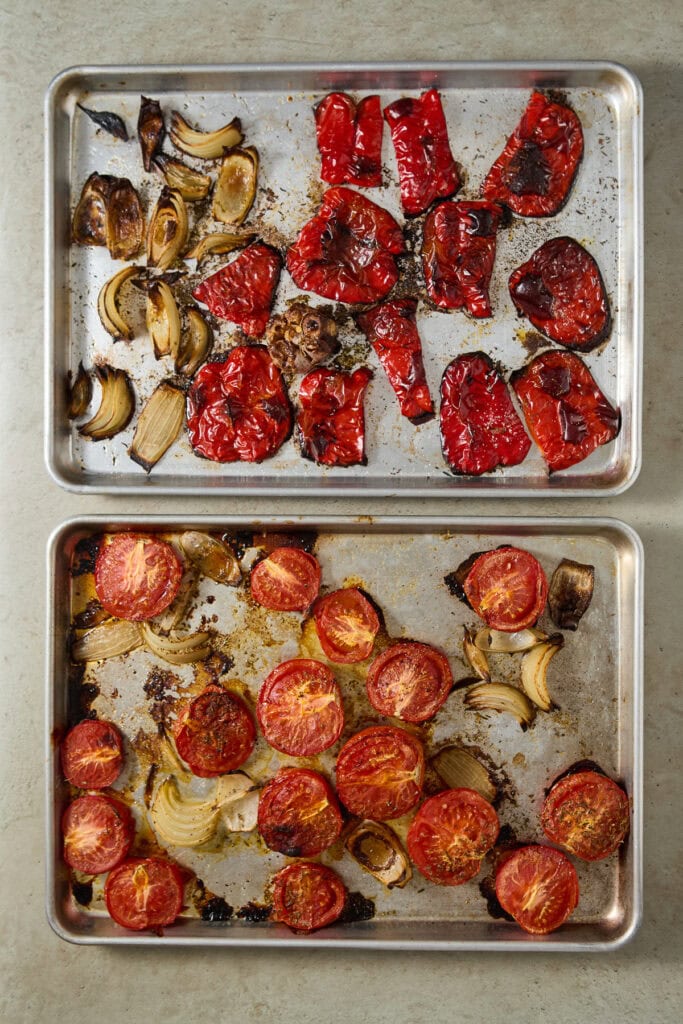 Roasted red peppers, cherry tomatoes, garlic, and onions on baking sheets, showcasing a delicious homemade roasted vegetable dish. Perfect for salads, pasta, or side dishes.