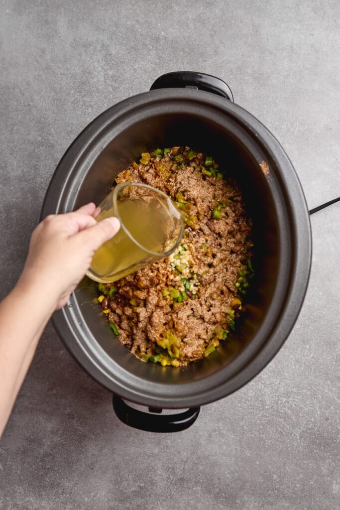 chicken stock being added to slow cooker of chicken tortilla soup