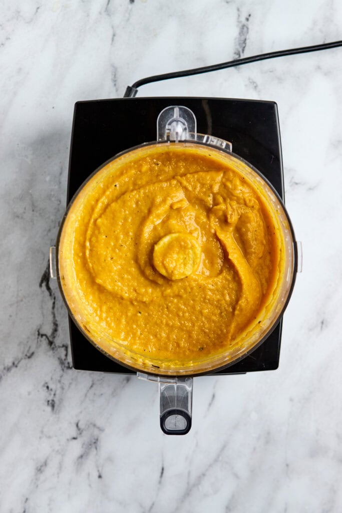 Creamy butternut squash pasta sauce in a blender, ready for blending, with a vibrant orange color, served as a comforting and delicious fall or winter soup option.