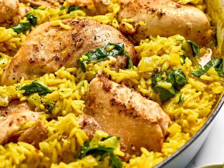 Juicy roasted chicken thighs with coconut curry rice and spinach in a skillet.