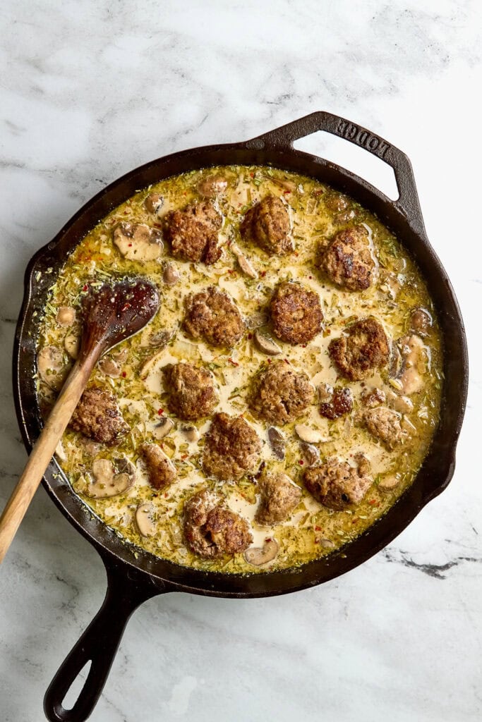 Savory meatballs cooking in creamy mushroom sauce in a cast iron skillet, highlighting comfort food recipes and easy dinner ideas.