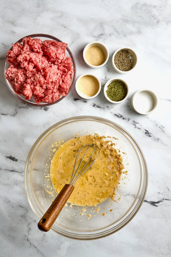 Minced meat with seasonings and herbs, ingredients for making meatball mixture at Stuck On Sweet.