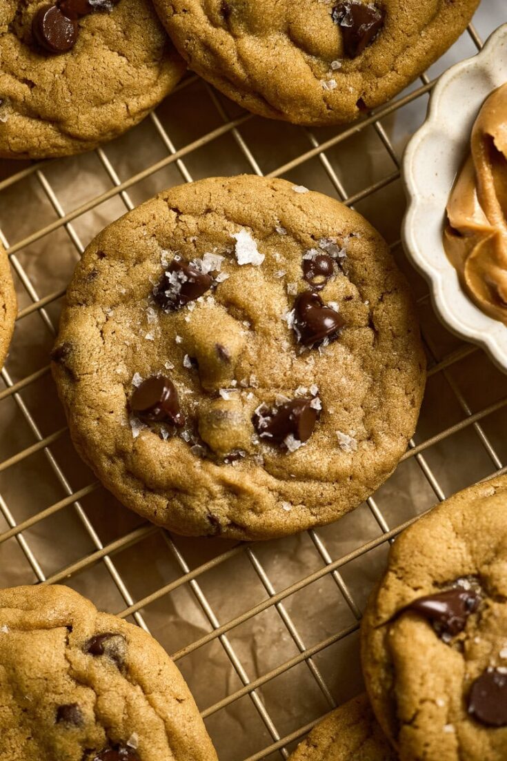 Chewy peanut butter chocolate chip cookies with sea salt on cooling rack, homemade baked treats from Stuck On Sweet bakery, perfect for dessert or snack.