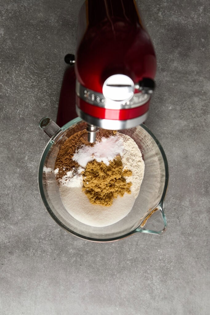 Close-up of a stand mixer blending brown sugar, flour, cocoa, and powdered sugar for delicious baked goods.