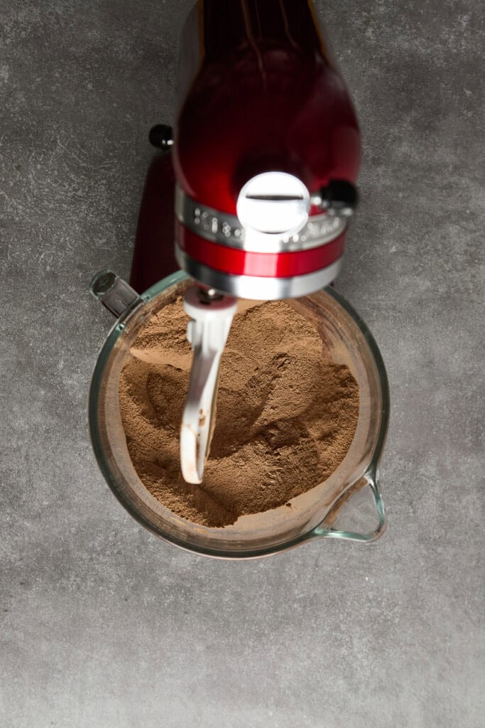Delicious chocolate powder mixed in a bowl with stand mixer, perfect for baking and dessert recipes, on a modern gray kitchen surface.