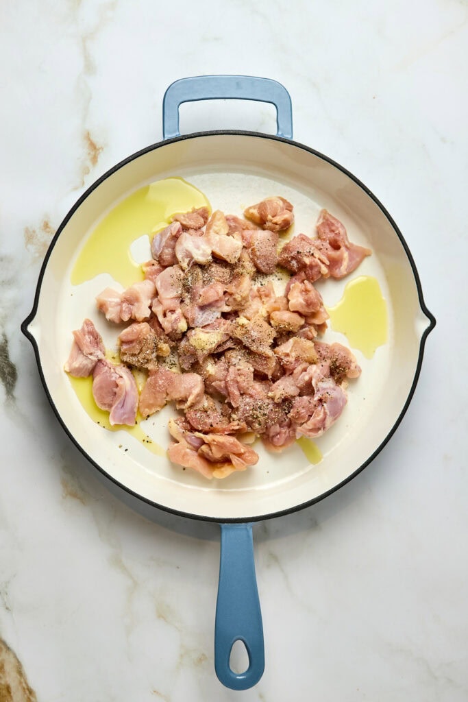 A skillet with raw chicken pieces seasoned with spices, olive oil, and prepared for cooking, showcasing a delicious chicken dish feature for food lovers, recipes, and culinary inspiration.