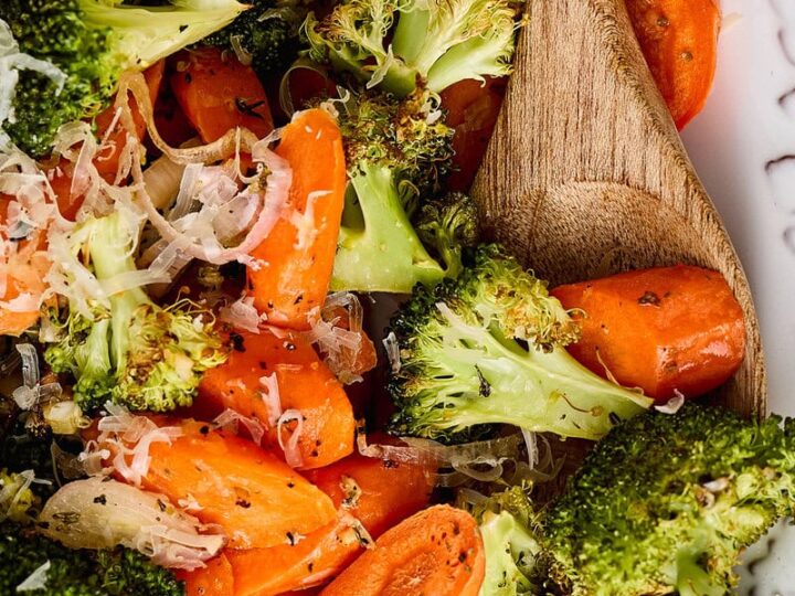 Roasted broccoli and carrots with lemon slice and creamy dressing, served with a wooden spoon. Perfect for healthy eating and vegetable lovers.