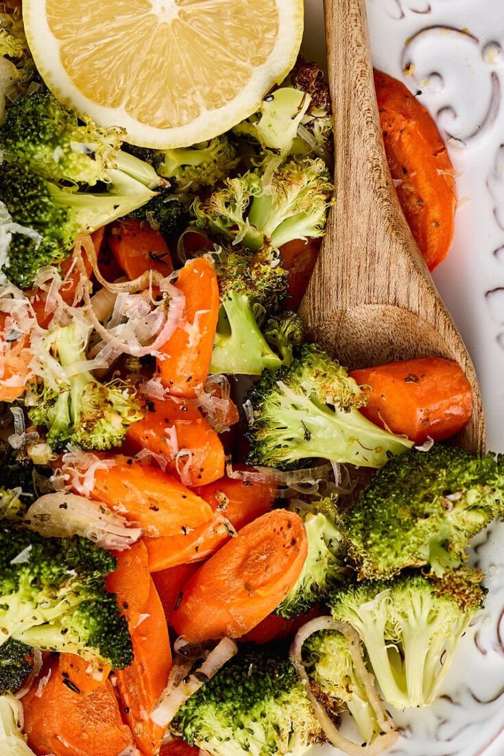 Roasted broccoli and carrots with lemon slice and creamy dressing, served with a wooden spoon. Perfect for healthy eating and vegetable lovers.