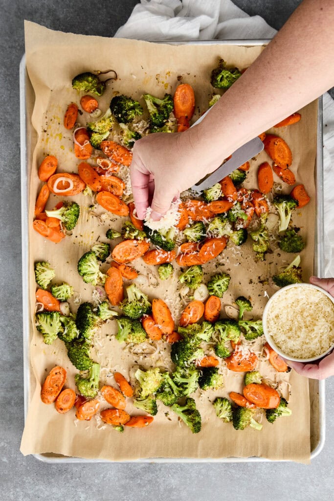 Healthy roasted broccoli and carrots with seasoning on parchment paper.
