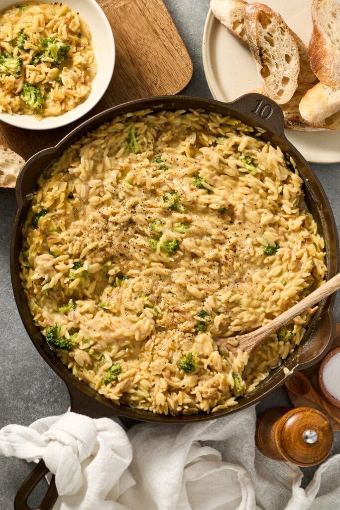 Hearty broccoli cheddar orzo skillet with fresh broccoli, served in a black cast iron skillet, perfect for comforting family dinners.