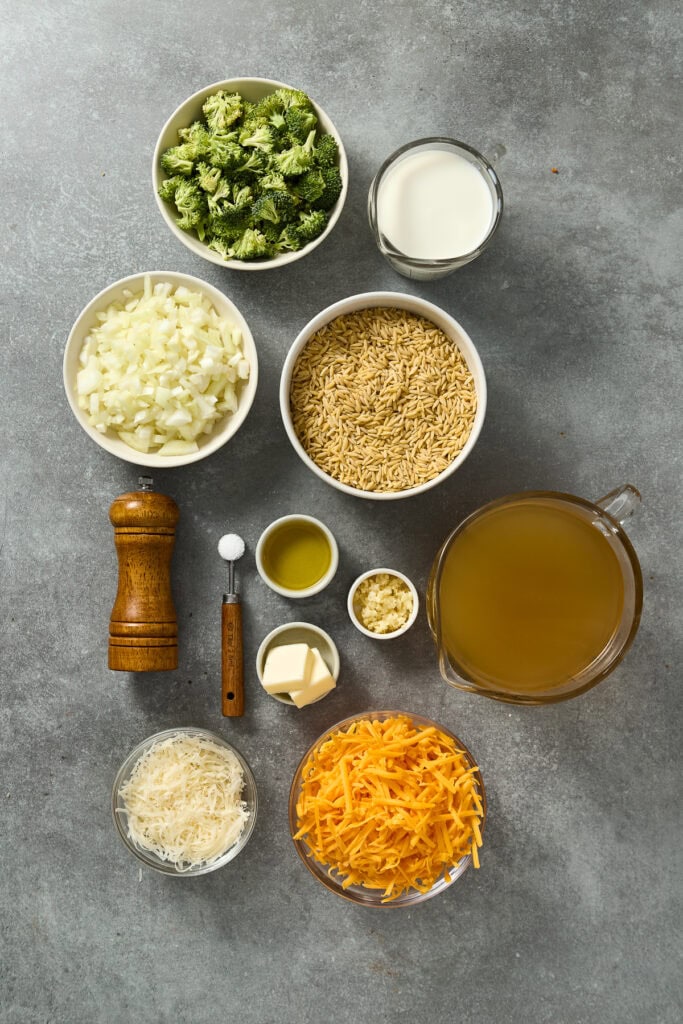 Fresh broccoli, shredded cheese, milk, rice, and seasonings for cheesy broccoli casserole preparation.