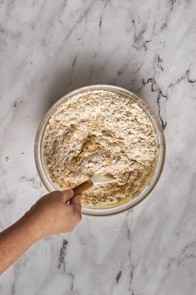 Bowl of cookie dough with oats and brown butter, ready to bake, on a marble surface. Perfect for making soft, chewy oatmeal cookies with rich brown butter flavor.
