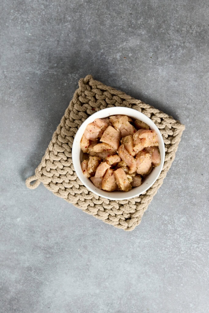 Crispy chicken Parmesan bites served in a white bowl on a textured gray surface, perfect for a delicious appetizer or snack.