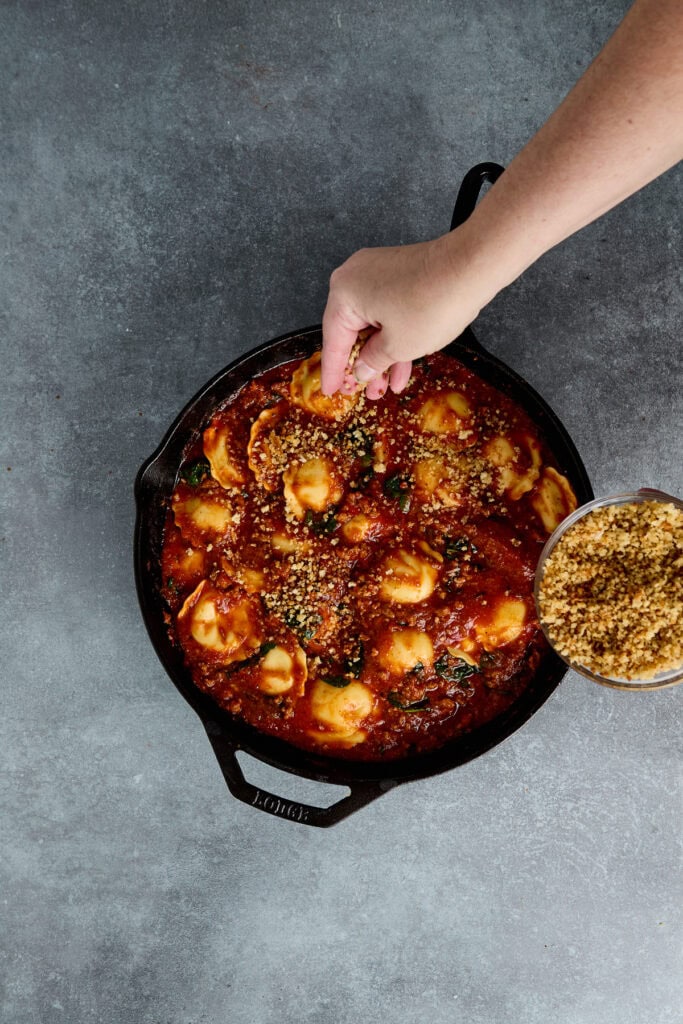 Delicious cheesy potato gnocchi being served in a rich tomato sauce, garnished with herbs and cheese, showcasing a comforting Italian-inspired dish.