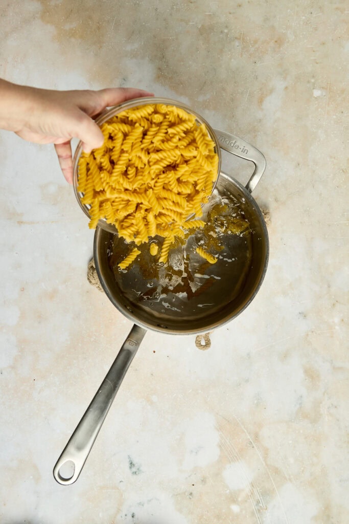 Delicious yellow pasta being poured into a skillet with melted butter or oil, ready for cooking. Perfect for Italian-inspired recipes or comfort food dishes.