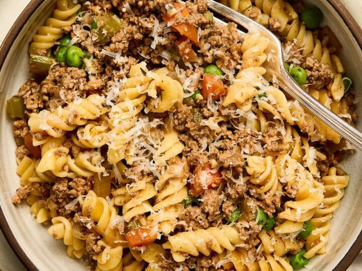 Hearty pasta dish with ground beef, peas, and diced vegetables served in a rustic bowl, perfect for a comforting meal.
