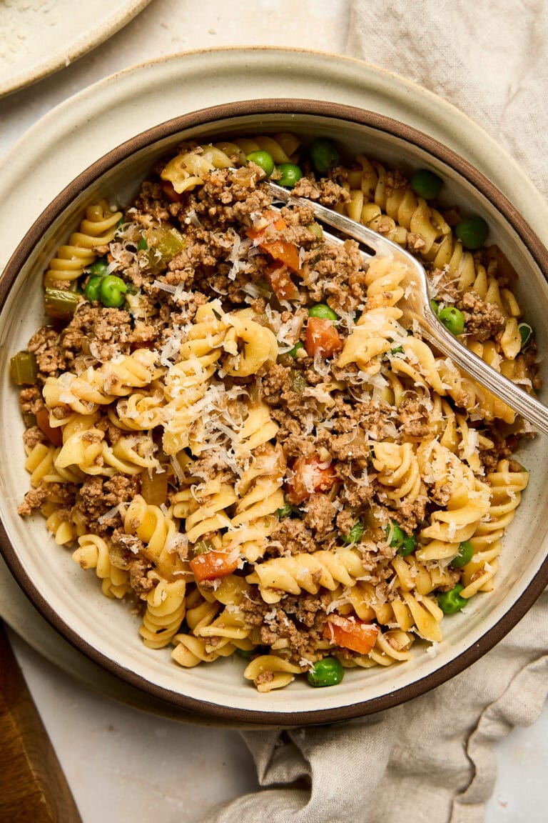 Hearty pasta dish with ground beef, peas, and diced vegetables served in a rustic bowl, perfect for a comforting meal.