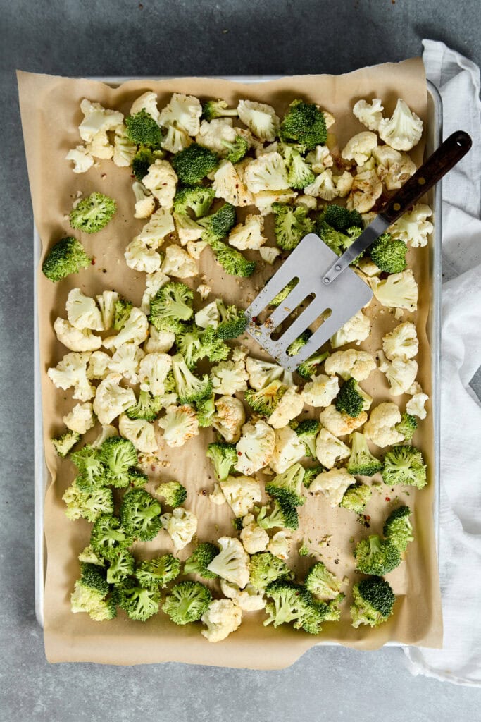 Fresh roasted cauliflower and broccoli florets on baking sheet, ready for seasoning or serving, showcasing healthy vegetable options for nutritious meals.