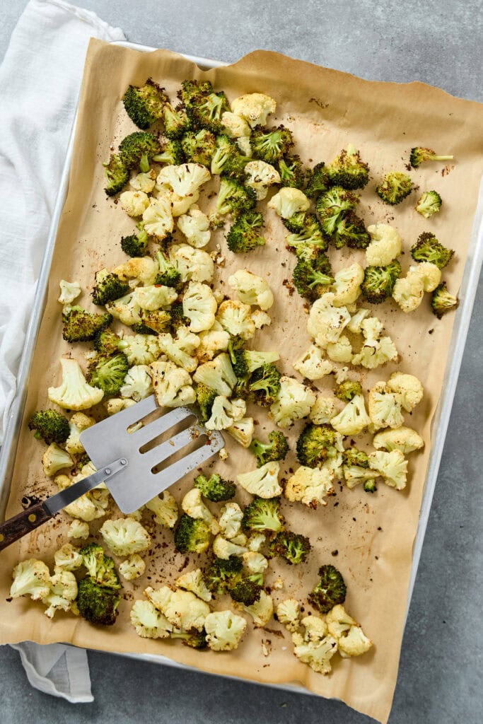 Baked cauliflower and broccoli florets on parchment paper, ready for serving or further preparation, showcasing healthy roasted vegetables.