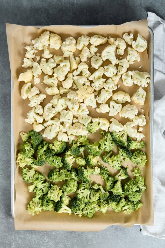 Cauliflower and broccoli florets arranged on a baking sheet, ready for roasting or cooking, showcasing fresh, healthy vegetables perfect for nutritious meals.