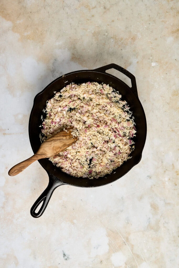 Basmati rice toasting in a black cast iron skillet.